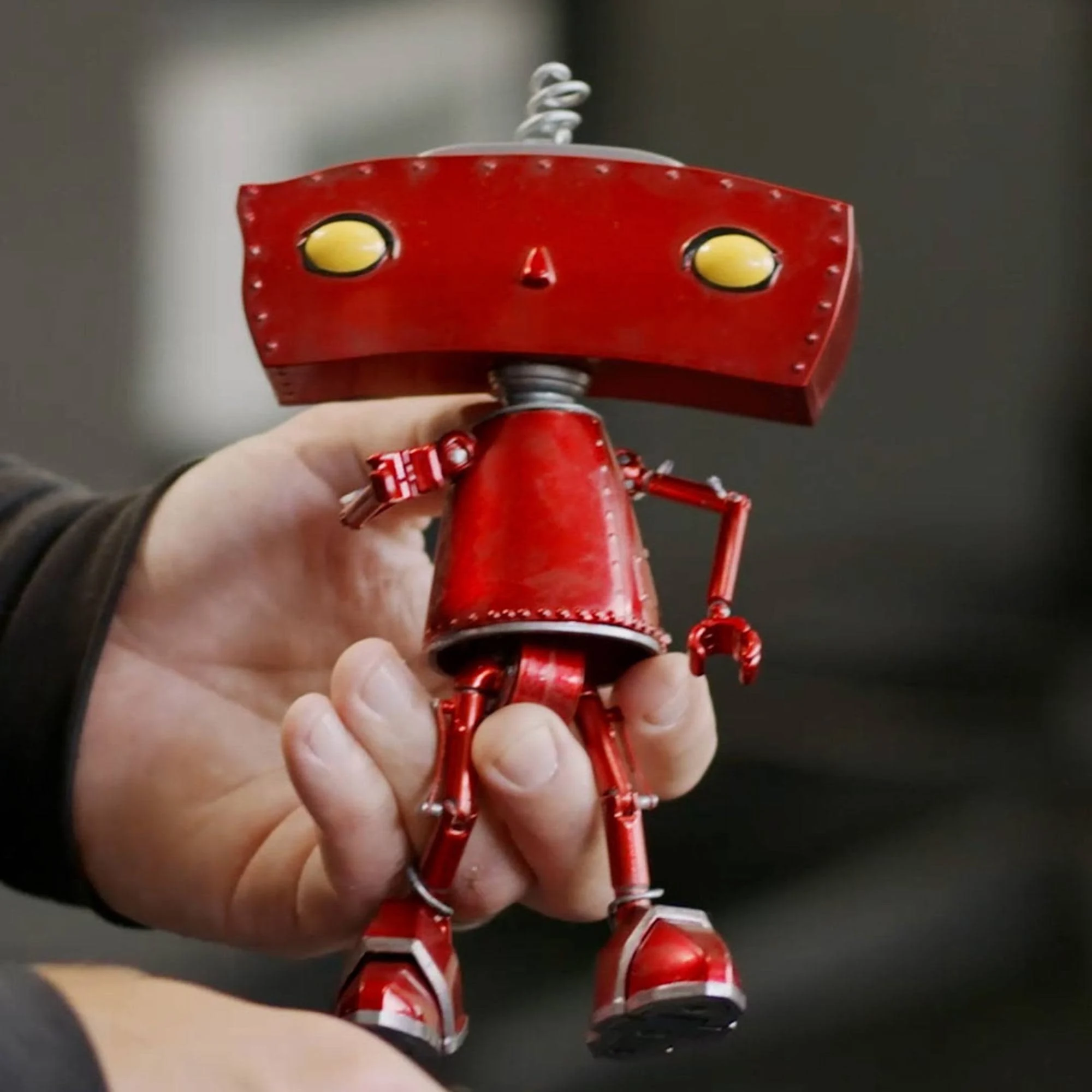 Bad Robot premium die-cast figure held in Adam's hand — red riveted head, articulated body